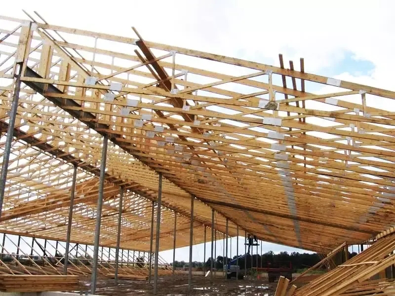 Large scale wooden roof trusses installed on steel support pillars for a commercial warehouse.