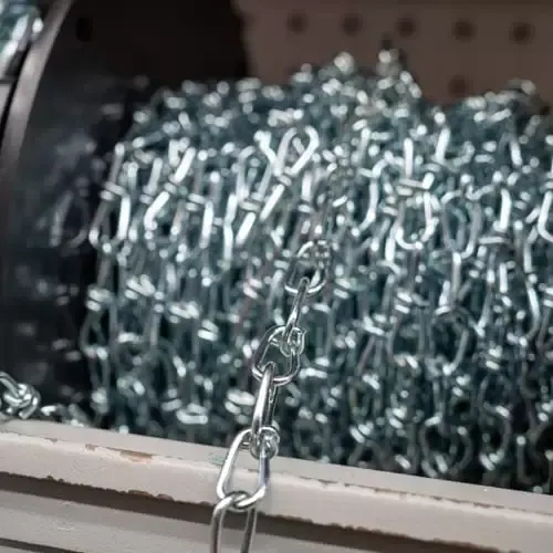 A close-up view of a spool of silver galvanized metal chain.